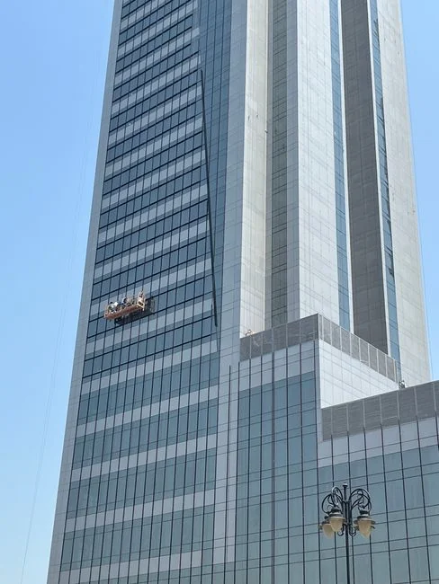 An adult male cleaning a glass window indoors, focusing on household chores and cleanliness.